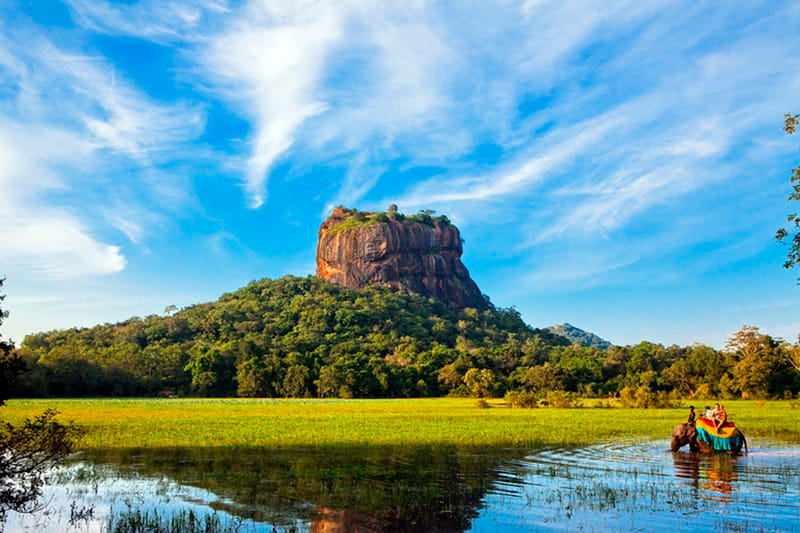 Sigiriya rock and locas riding an elephant