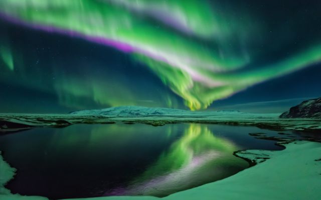 The Northern lights at night illuminating a lake, Iceland