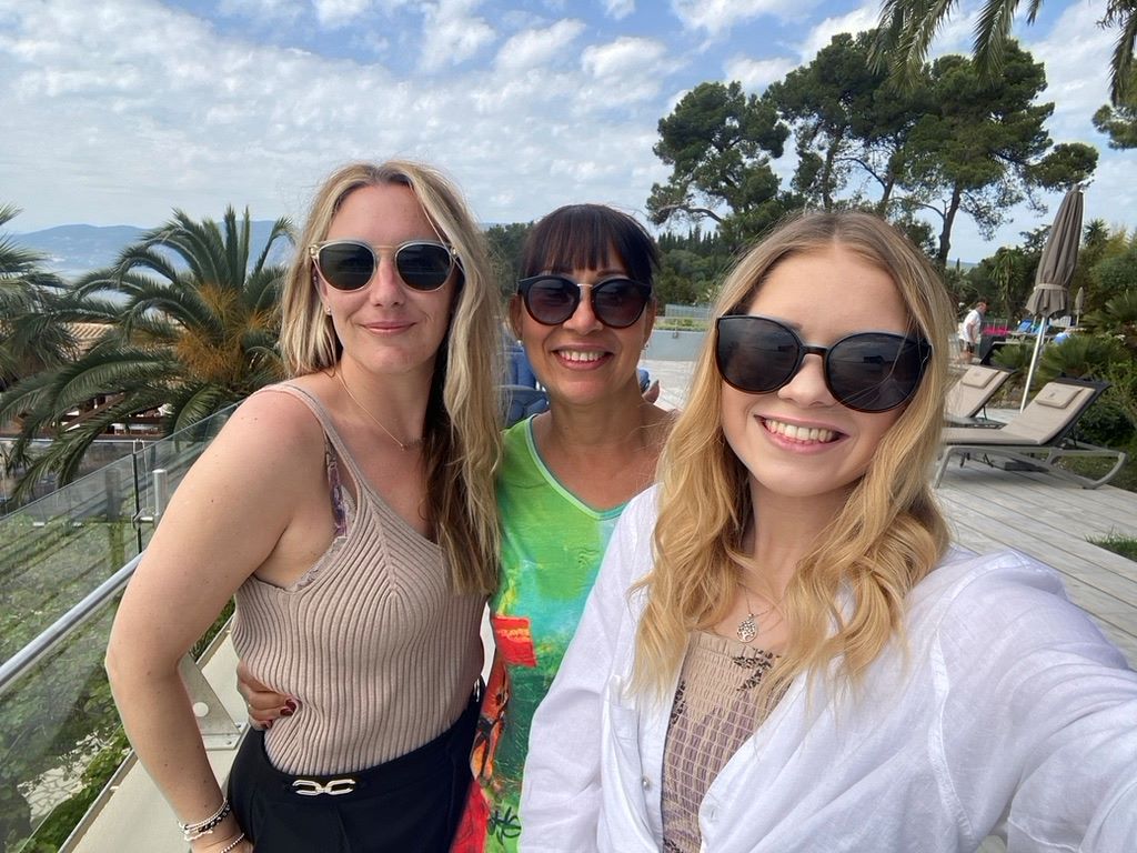 Three people smiling on a balcony in Corfu Greece